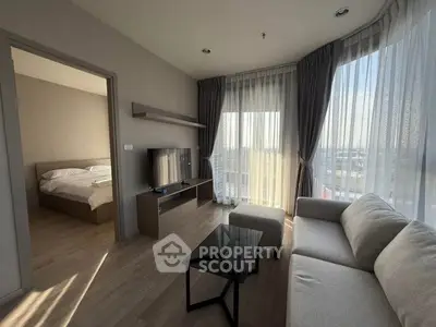 Modern living room with large windows and natural light, featuring a cozy sofa and sleek TV setup.