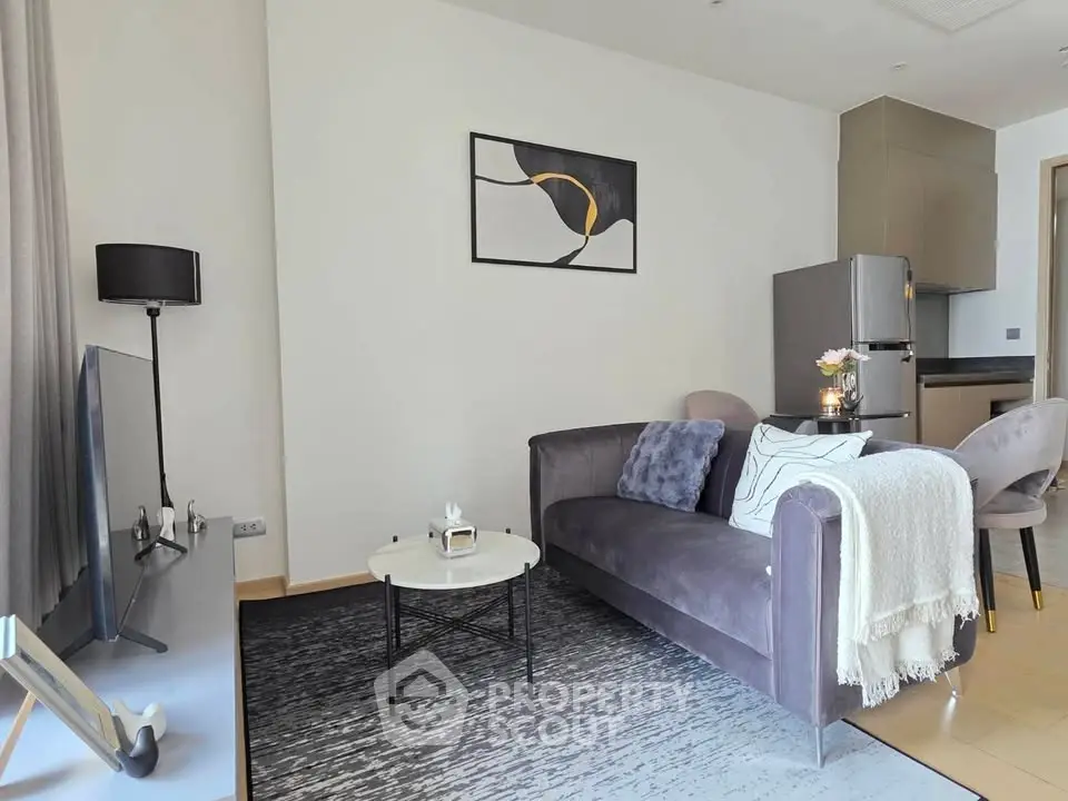 Modern living room with stylish decor and open kitchen layout, featuring a cozy sofa and contemporary artwork.