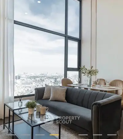 Luxurious living room with floor-to-ceiling windows offering stunning city views, elegant decor, and cozy seating.