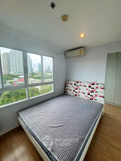 Spacious bedroom with large window offering stunning city views and modern furnishings.