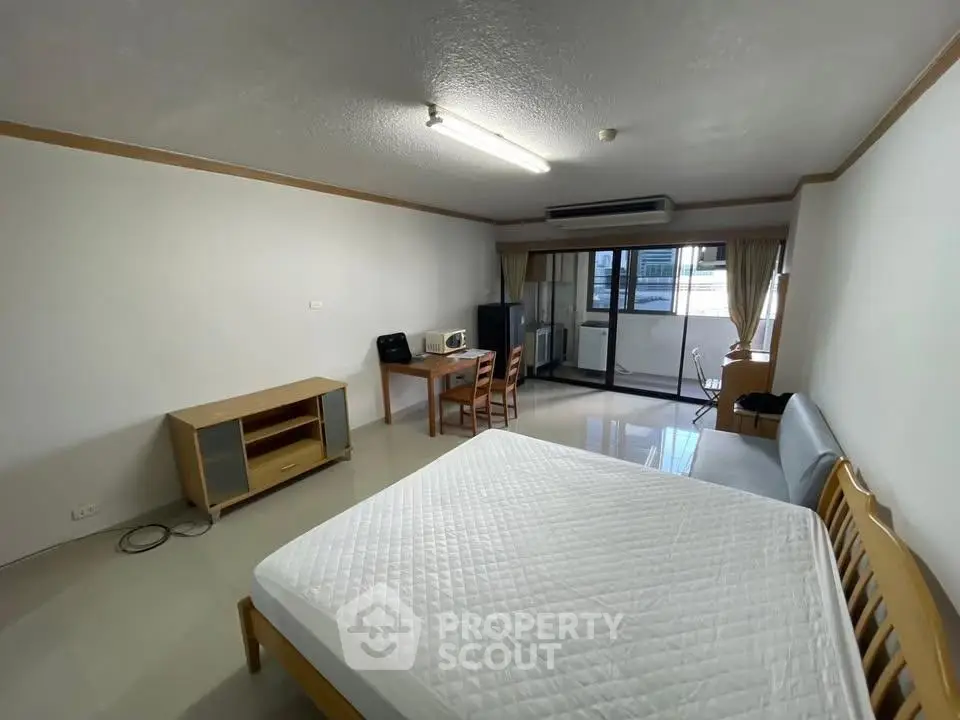 Spacious studio apartment with modern furnishings and large windows for natural light.