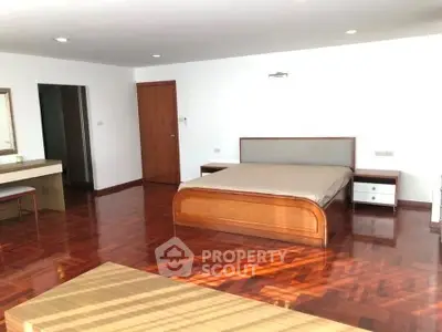 Spacious bedroom with wooden flooring and modern furnishings in a luxury apartment.