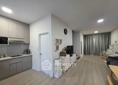 Modern open-layout living room with sleek kitchen, stylish decor, and cozy ambiance.