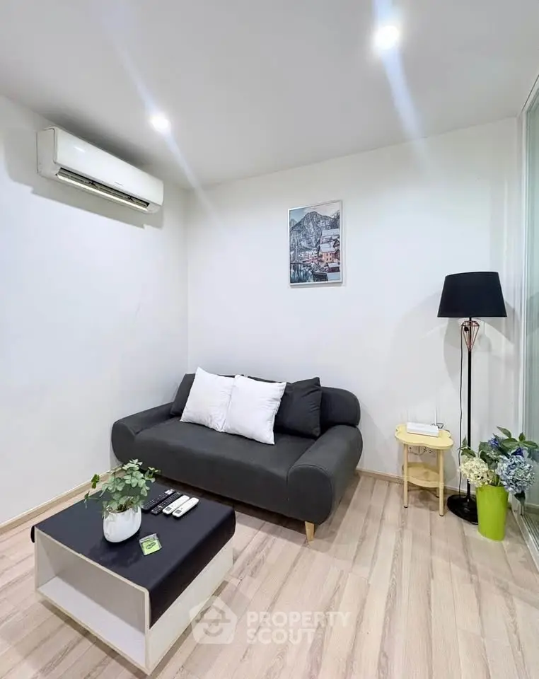 Modern living room with sleek black sofa, stylish decor, and air conditioning in a cozy apartment.