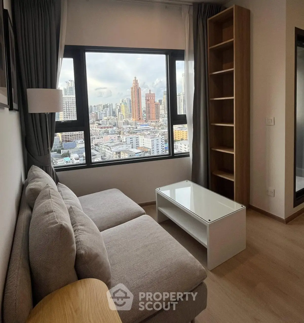 Modern living room with city view, featuring a cozy sofa and sleek coffee table.