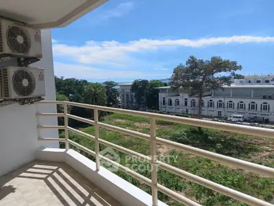 Spacious balcony with scenic view of lush greenery and modern buildings, perfect for relaxation.