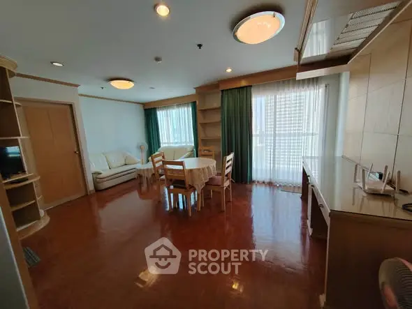 Spacious living room with wooden flooring and large windows in a modern apartment.