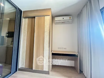 Modern bedroom with built-in wardrobe and air conditioning unit, featuring sleek wooden finishes.
