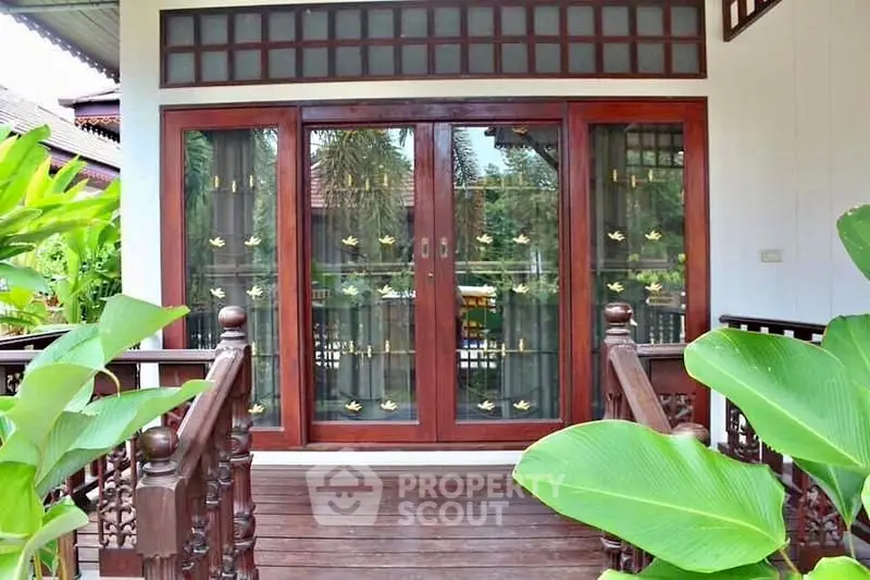 Charming wooden entrance with glass doors and lush greenery