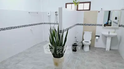 Spacious modern bathroom with sleek tile design and stylish plant decor.