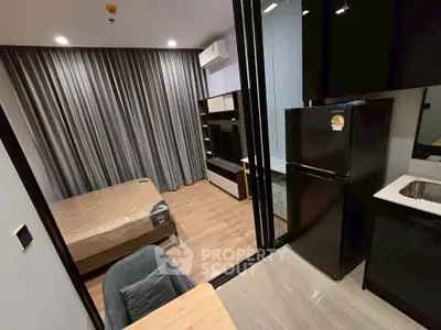Modern studio apartment with sleek design, featuring a cozy bedroom and compact kitchen area.