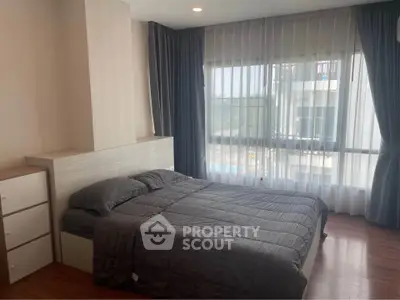 Spacious bedroom with large windows and modern decor in a luxury apartment.