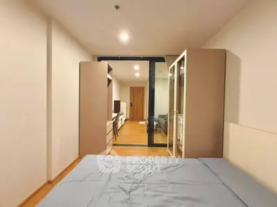 Modern bedroom with sleek design and glass partition leading to living area.