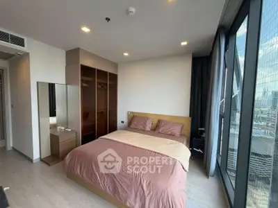Modern bedroom with city view, featuring a cozy bed and ample closet space in a high-rise apartment.