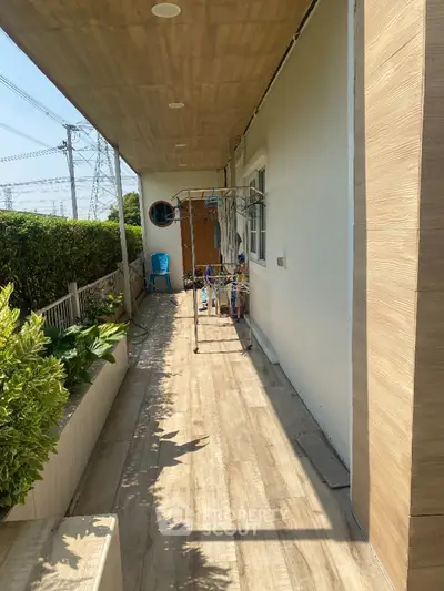 Spacious balcony with wooden flooring and lush greenery, perfect for relaxation and outdoor activities.
