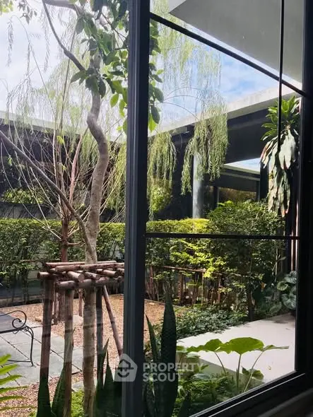 Stunning garden view from modern building window, showcasing lush greenery and serene outdoor ambiance.