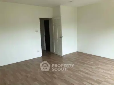 Spacious empty room with wooden flooring and white walls, ready for customization.