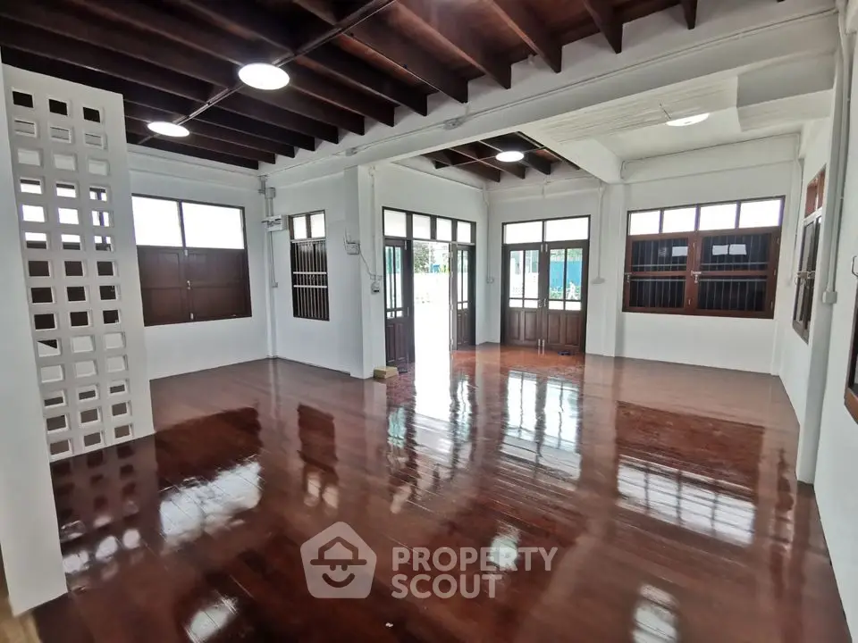 Spacious open-plan living area with polished wooden floors and large windows