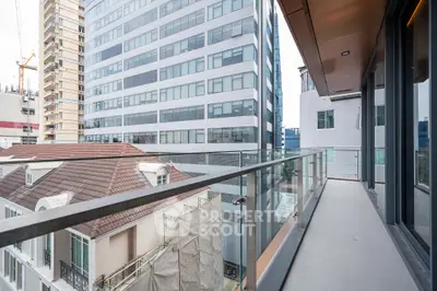 Modern apartment balcony with glass railing offering cityscape views.