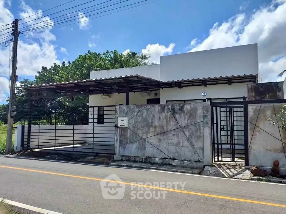 Modern single-story house with gated entrance and carport on a sunny day.