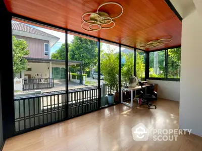 Spacious sunlit room with modern decor and large windows overlooking a garden view.