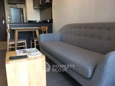 Modern living room with stylish gray sofa and compact dining area in open layout.