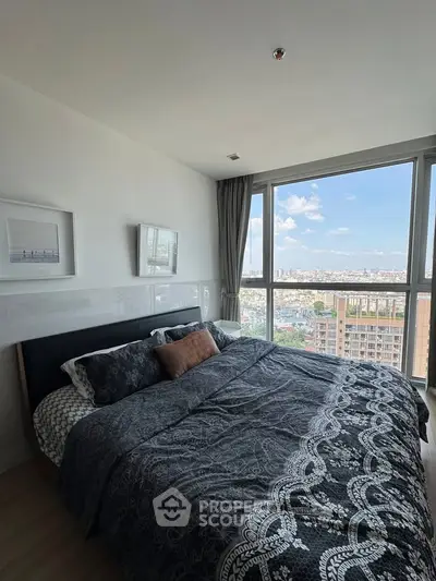 Spacious bedroom with large window offering stunning city views, modern decor, and cozy bedding.
