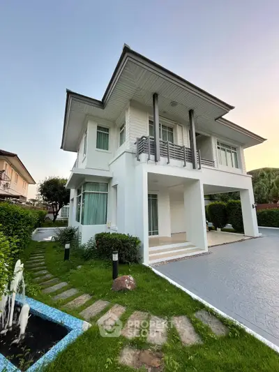 Modern two-story house with lush garden and driveway in serene neighborhood.