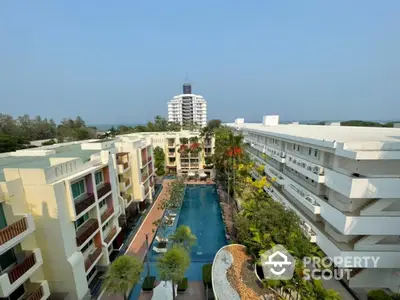 Stunning aerial view of luxury apartment complex with central pool and lush greenery.