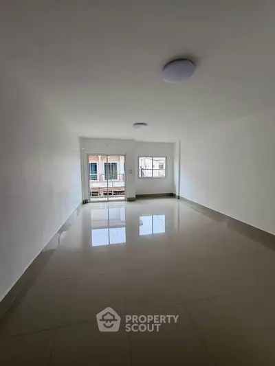 Spacious unfurnished living room with large windows and tiled flooring, perfect for customization.