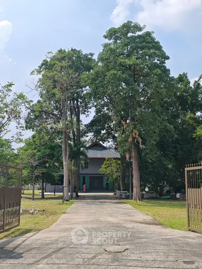 Charming property entrance with lush greenery and spacious driveway