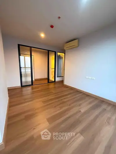 Spacious modern bedroom with wooden flooring and glass partition in a stylish apartment.