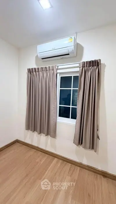 Cozy bedroom with air conditioning and wooden flooring, perfect for comfortable living.