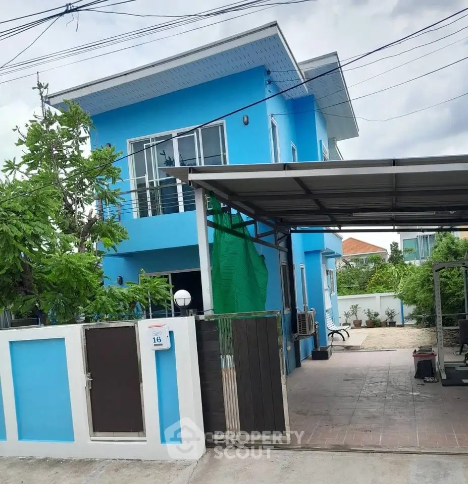 Charming blue two-story house with gated entrance and spacious driveway, perfect for family living.