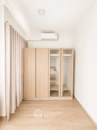 Minimalist bedroom with wooden wardrobe and air conditioning in modern apartment.