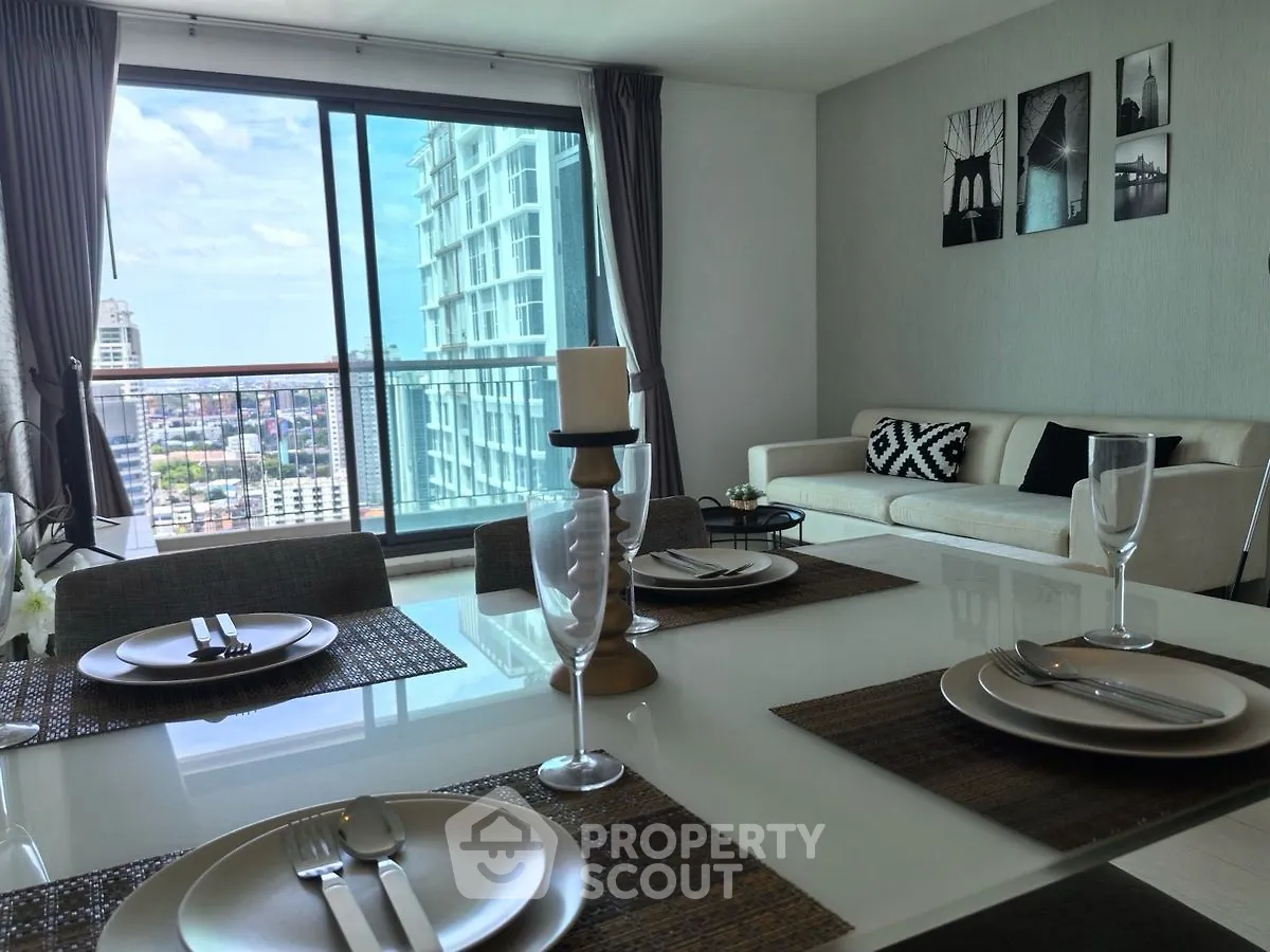 Modern living room with dining area and city view balcony in high-rise apartment.