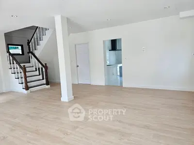 Spacious open-plan living area with wooden flooring and elegant staircase