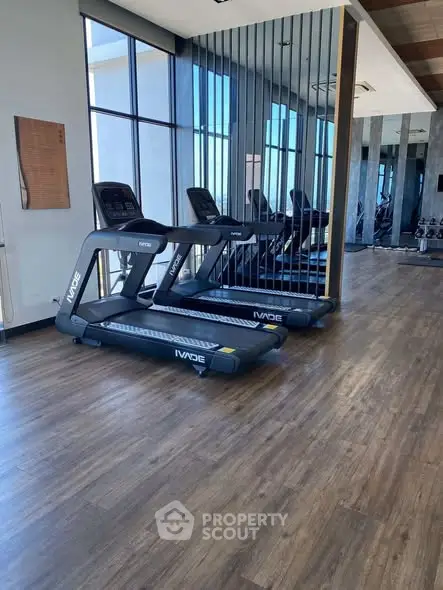 Modern gym with treadmills and mirrored walls in luxury apartment building.