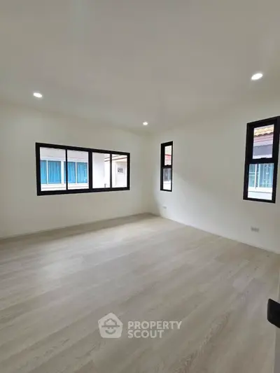Spacious empty room with large windows and wooden flooring