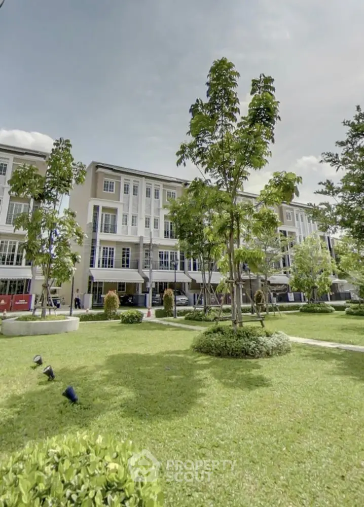 Modern townhouse complex with lush green landscaping and spacious outdoor area.