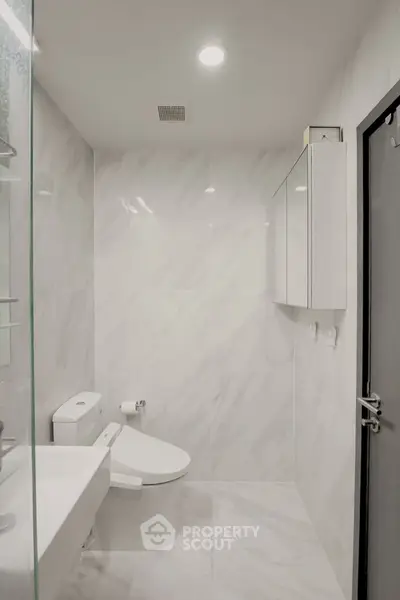 Modern minimalist bathroom with sleek white fixtures and marble walls