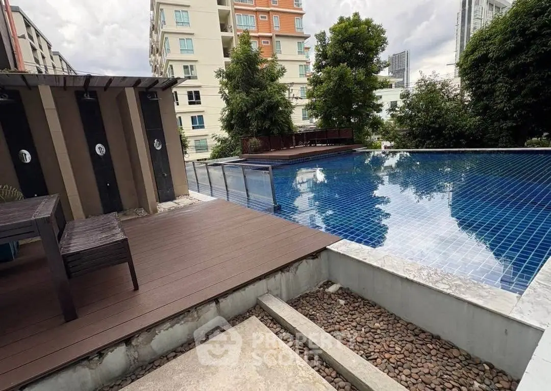 Luxurious rooftop pool with wooden deck and city view in modern apartment complex.