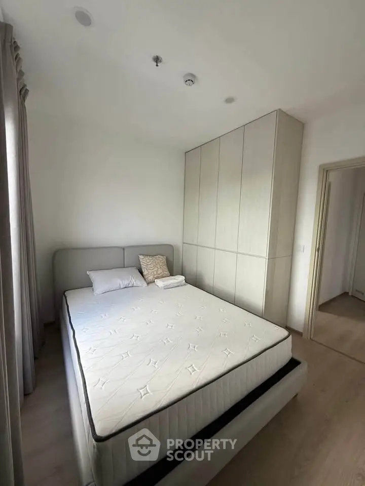 Modern bedroom with minimalist design and built-in wardrobe, featuring a comfortable bed and natural light.