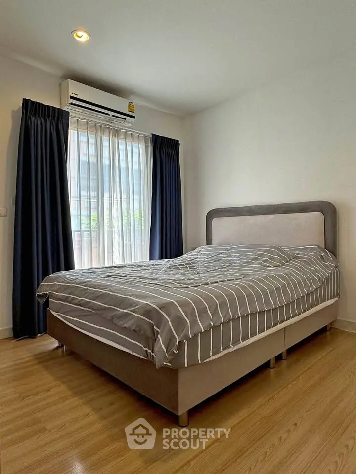 Cozy bedroom with modern decor and large window for natural light.