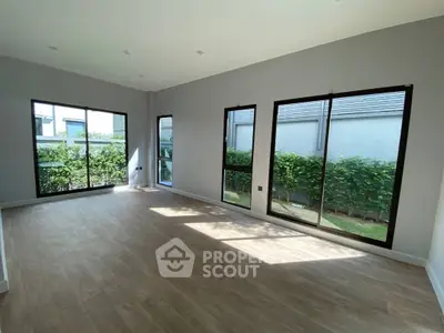 Spacious empty room with large windows and garden view, perfect for customization.