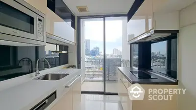 Sleek modern kitchen with high-end appliances, ample counter space, and a breathtaking city view through floor-to-ceiling glass doors leading to a balcony.