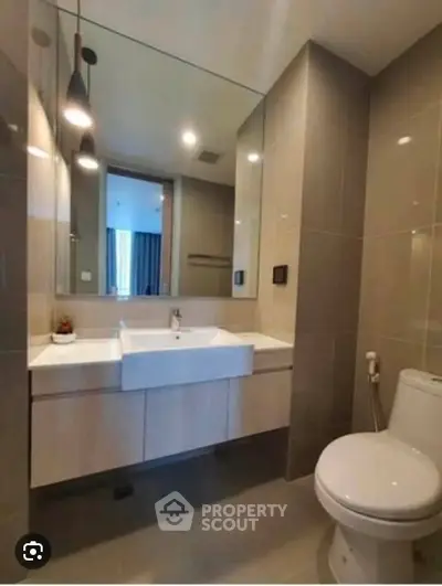 Modern bathroom with sleek fixtures and large mirror in a contemporary apartment.
