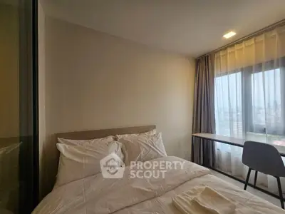 Cozy bedroom with city view, featuring a comfortable bed and a work desk by the window.