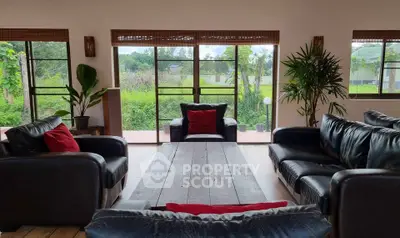 Spacious living room with leather sofas and lush garden view