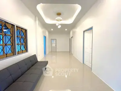 Spacious modern living room with sleek tile flooring and stylish ceiling lights.